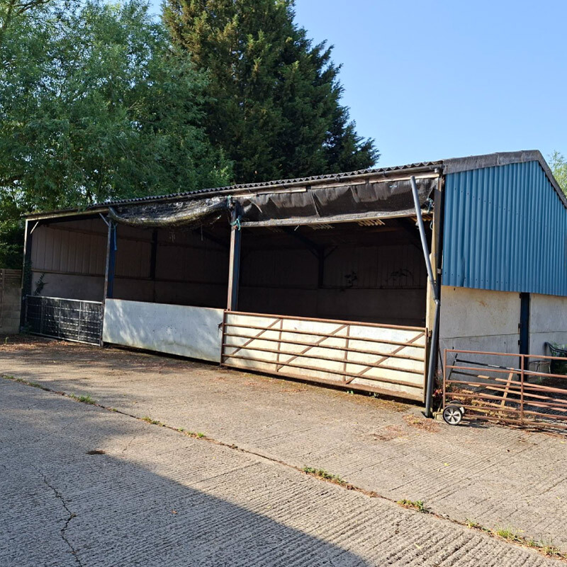 Picture of a barn that has multiple openings with all of them opened up with a blue roof and side panel